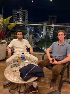 Daniel and a friend on a rooftop terrace at night in Colombia, a city behind them